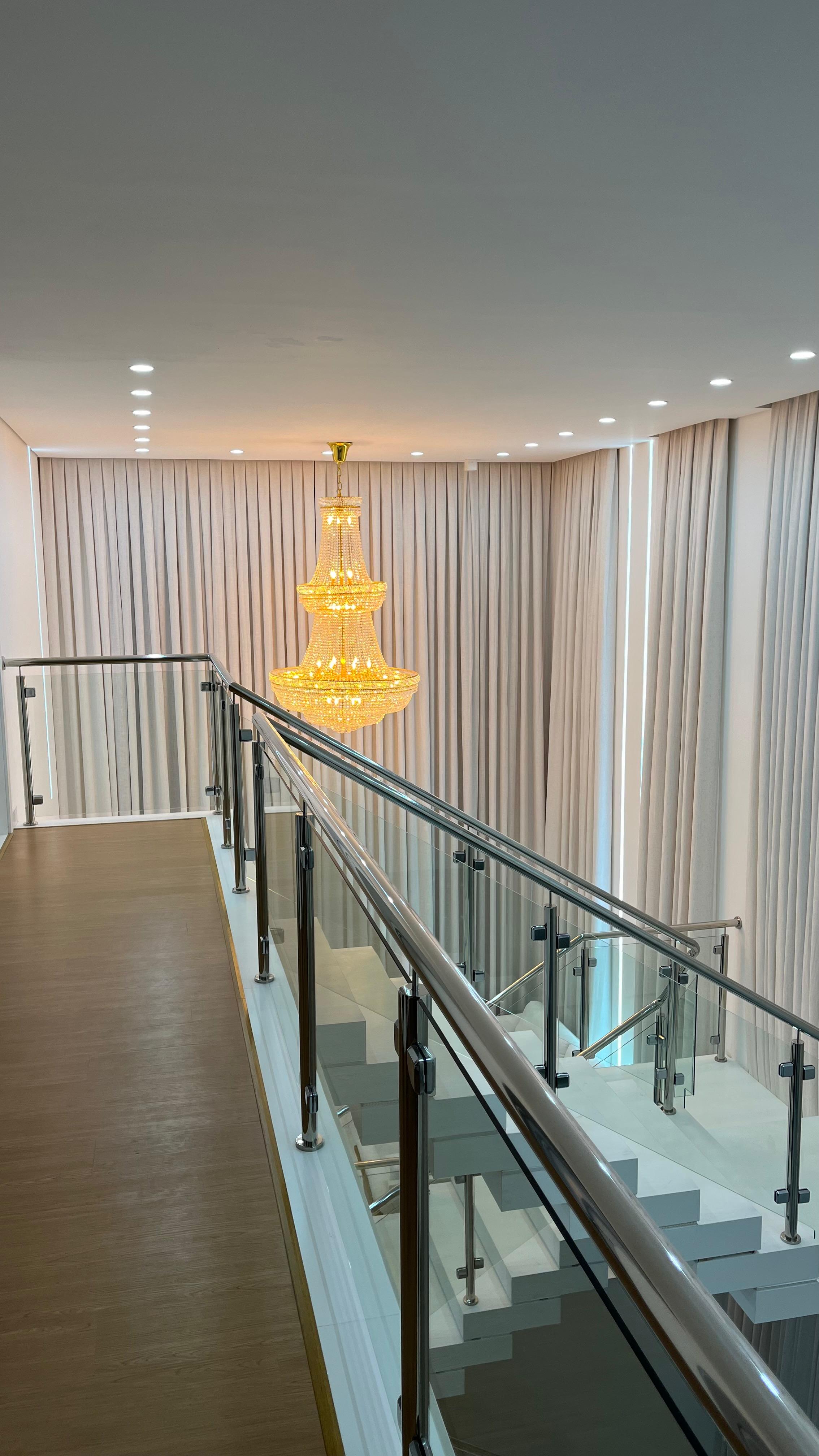 Corredor com cortina de voil do piso ao teto e lustre de cristal