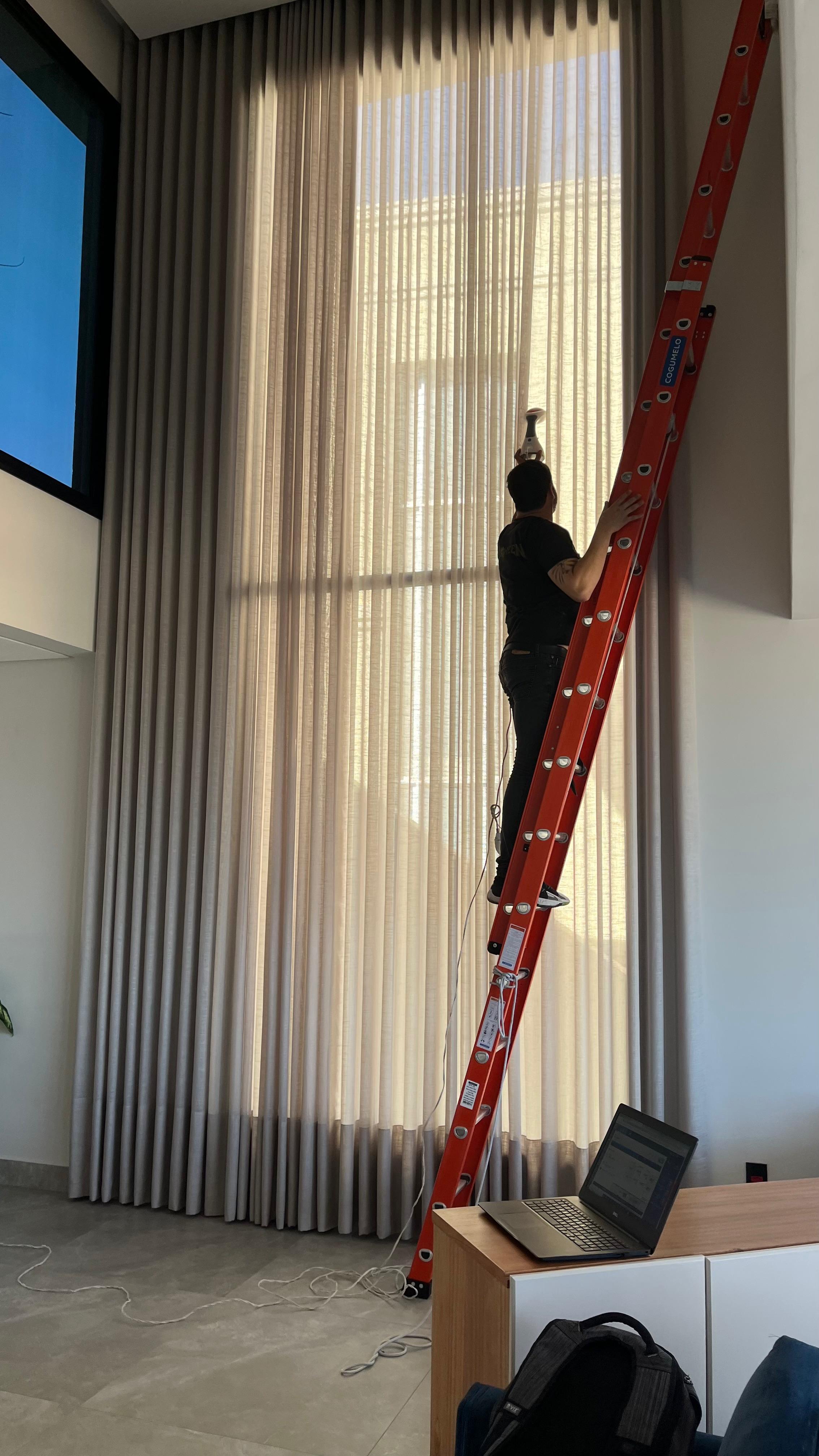 Instalador da SrHouse Decor no alto da escada fixando cortina de voil