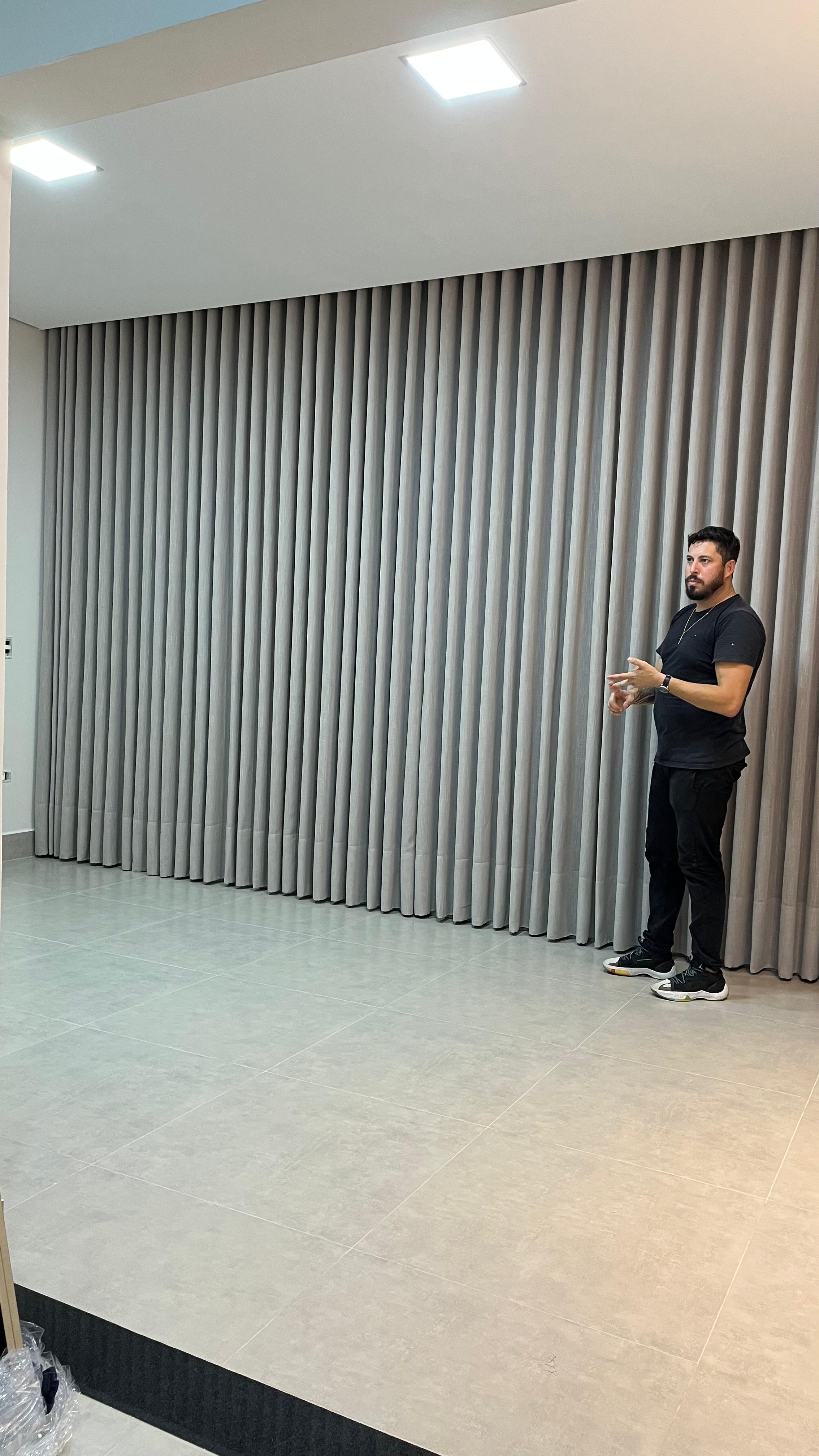 Instalador da SrHouse Decor observando cortina de voil finalizada em parede ampla